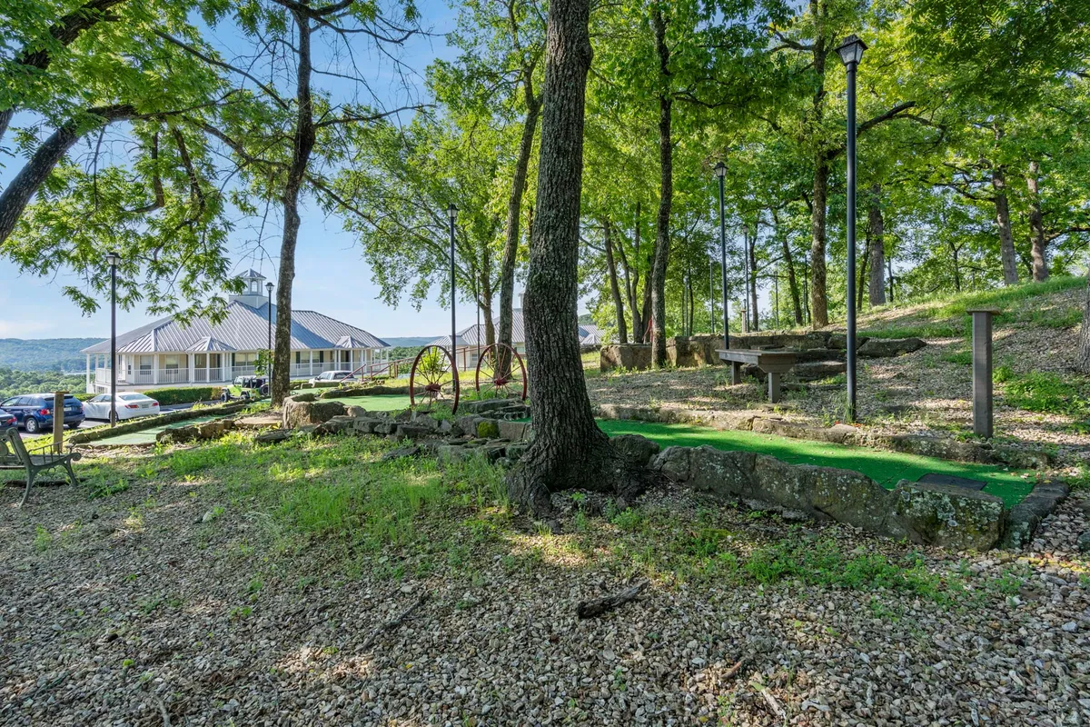 A lush, green mini-golf area framed by stone pathways and scenic views, surrounded by nature. The setting looks playful yet peaceful, inviting guests to enjoy outdoor activities in a serene environment.