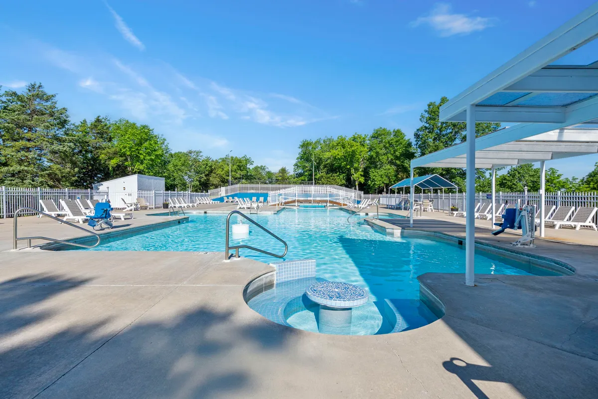 An inviting exterior shot of the swimming pool, hot tub, lounge chairs, and surrounding trees. The pool area looks refreshing, leisurely, and perfect for unwinding or socializing during a romantic escape.