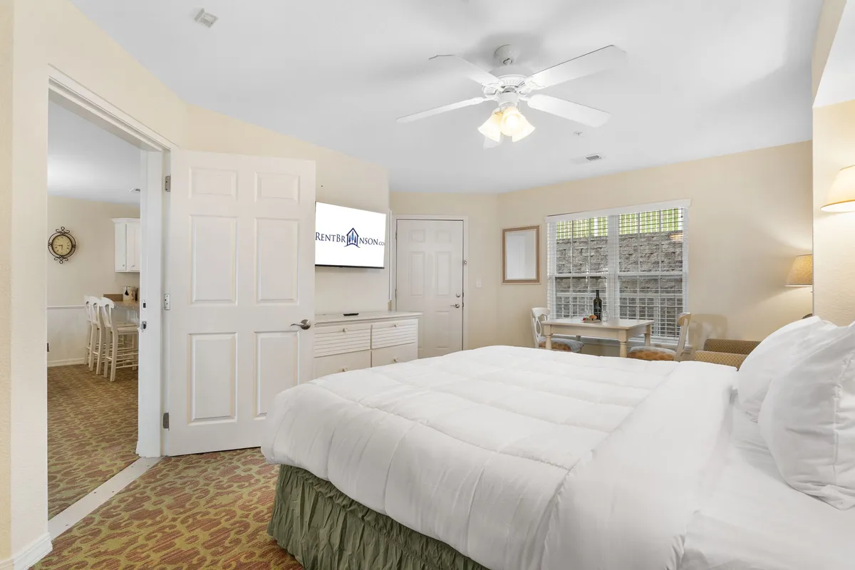 A cozy king bedroom with a bed, dining table, window, and television, radiating a welcoming and restful atmosphere. The setup suggests flexibility—guests can relax in bed, read, or enjoy a meal in a private retreat.