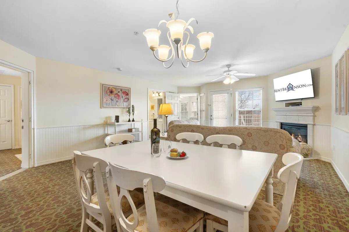 An open-concept space with a dining table, a glowing fireplace, a television, and ambient lighting. This area is designed for family dinners, relaxed evenings, and game nights, all within a warm, cozy environment.