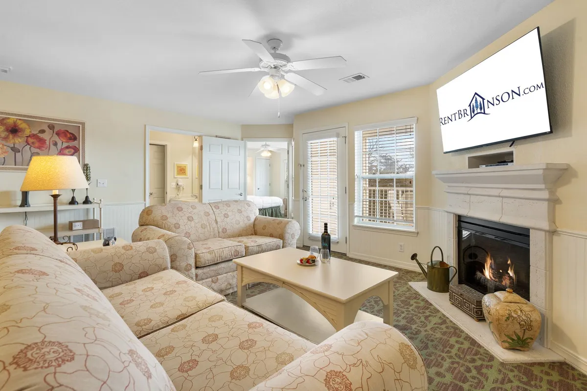 A cozy living room featuring a comfortable sofa, a coffee table set for relaxing, a welcoming fireplace, and a television. The soft lighting and tasteful decor create a relaxing setting perfect for socializing, playing games, or unwinding after a day outdoors.