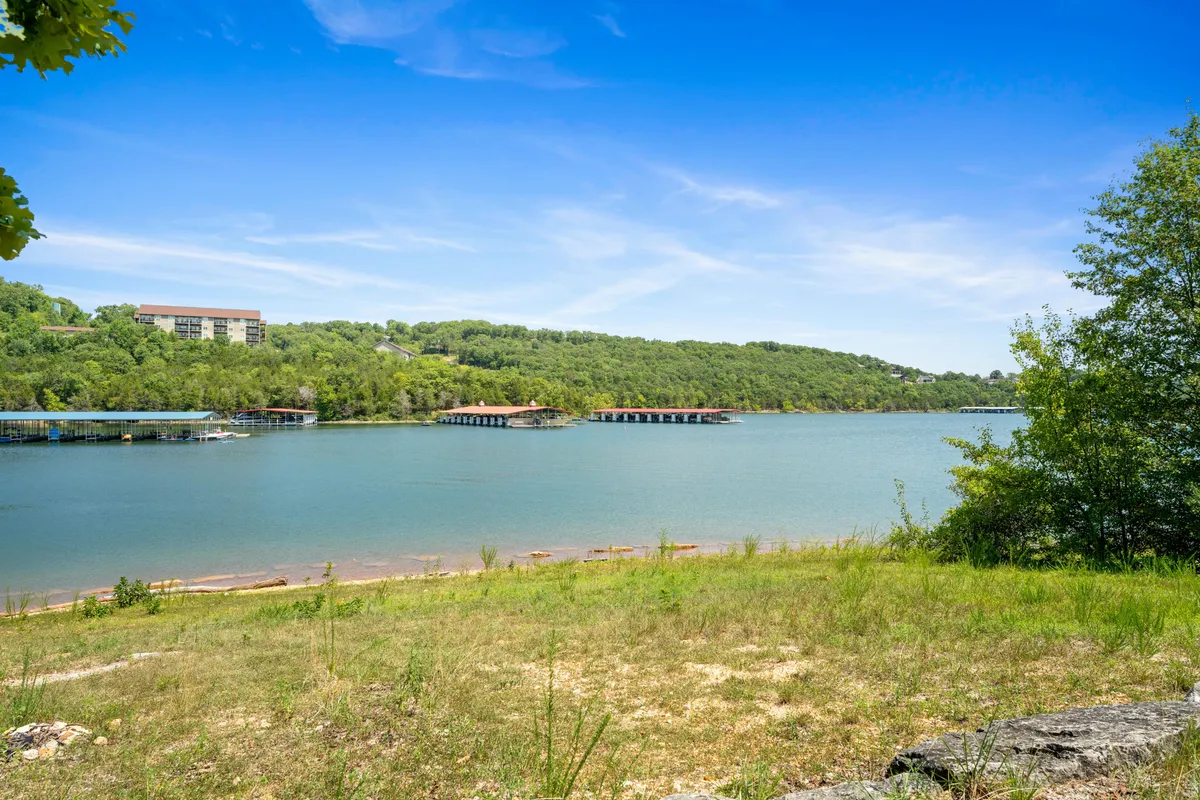 A tranquil lake framed by green hills stretches into the horizon, dotted with docks ready for boating and fishing. The scene suggests easy access to water sports and the promise of peaceful mornings or vibrant group outings.